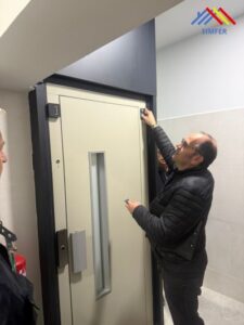 Técnico revisando la instalación de una puerta de ascensor en un portal reformado, con el logotipo de Simfer en la esquina.