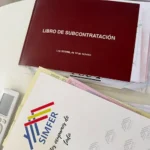 Libro de Subcontratación de la Ley 32/2006 sobre una mesa, junto a documentación de obra y una carpeta con el logotipo de SIMFER.