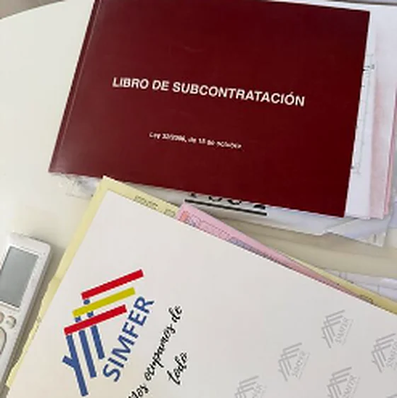 Libro de Subcontratación de la Ley 32/2006 sobre una mesa, junto a documentación de obra y una carpeta con el logotipo de SIMFER.